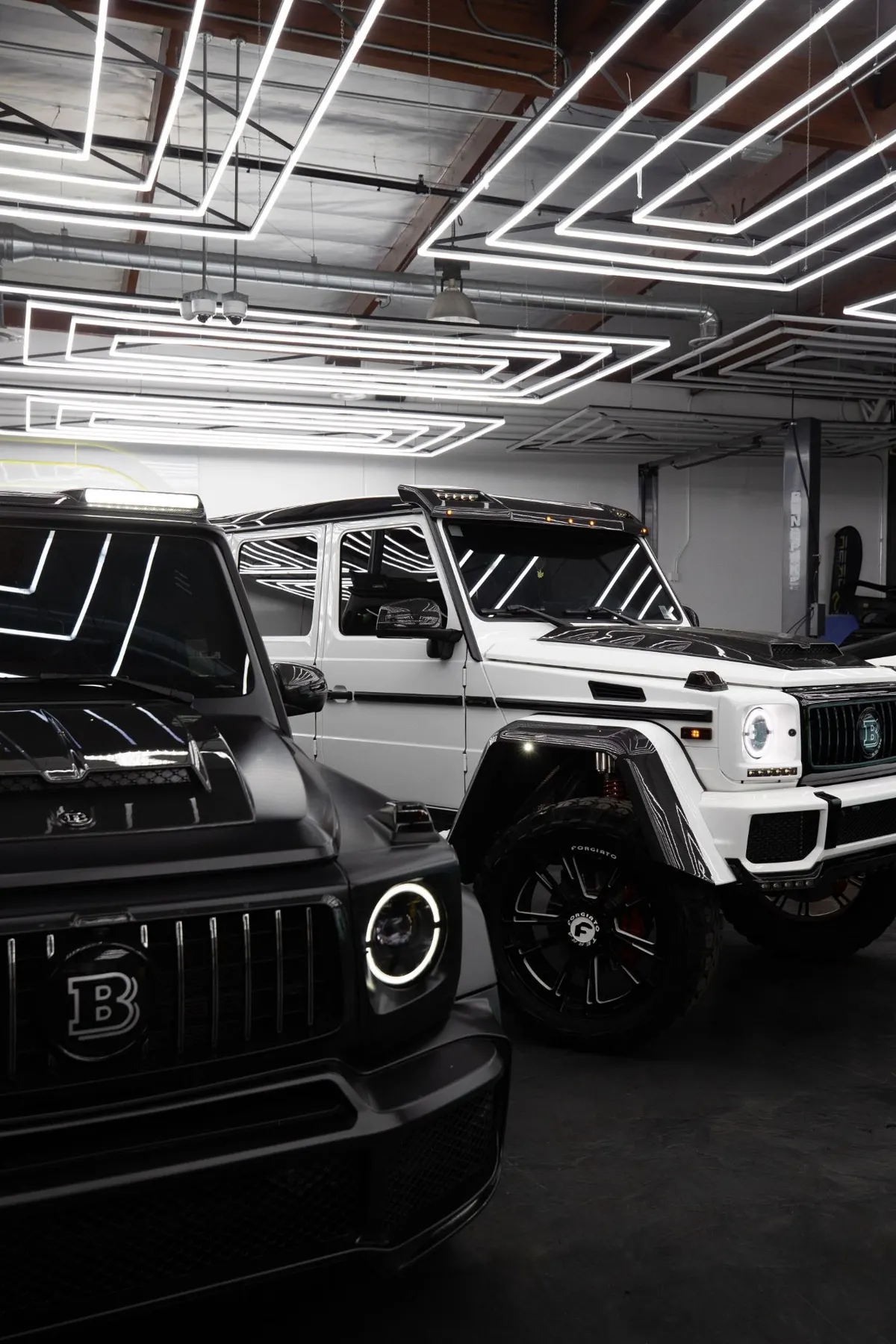 Zwei Luxus-Geländewagen in einer Garage mit Neonbeleuchtung