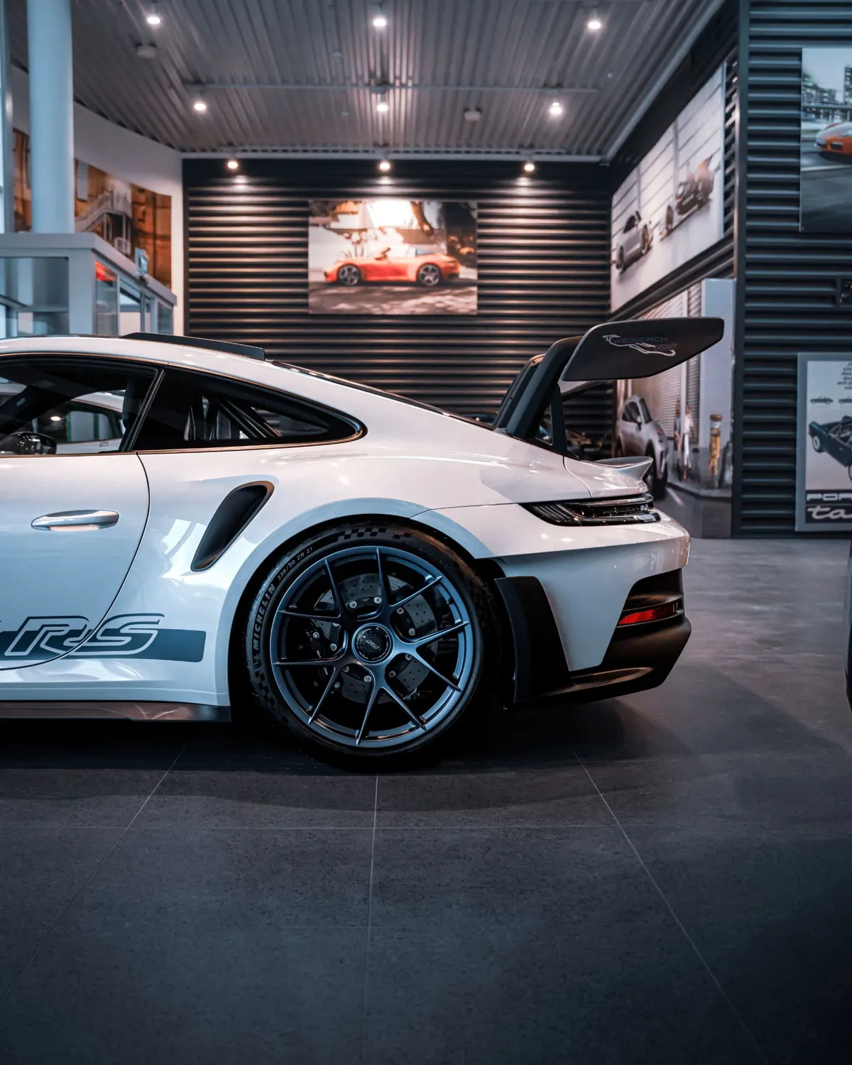 Das Heck eines weißen Sportwagens mit großem Heckflügel im Showroom